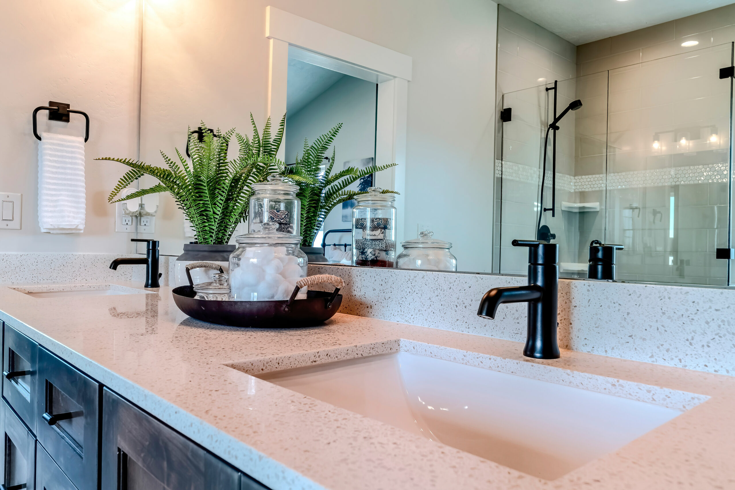 Double sink bathroom vanity with black faucet and white countertop over cabinets