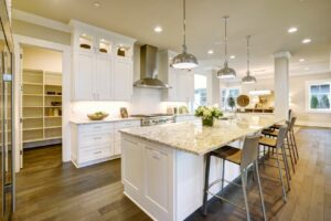 Modern kitchen with granite countertops, white cabinets, and an island with stools