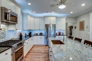 Spacious kitchen with new appliances, white cabinets, and grey/white/black countertops