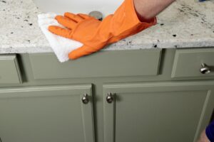 Person wiping white and black countertop with white hand towel