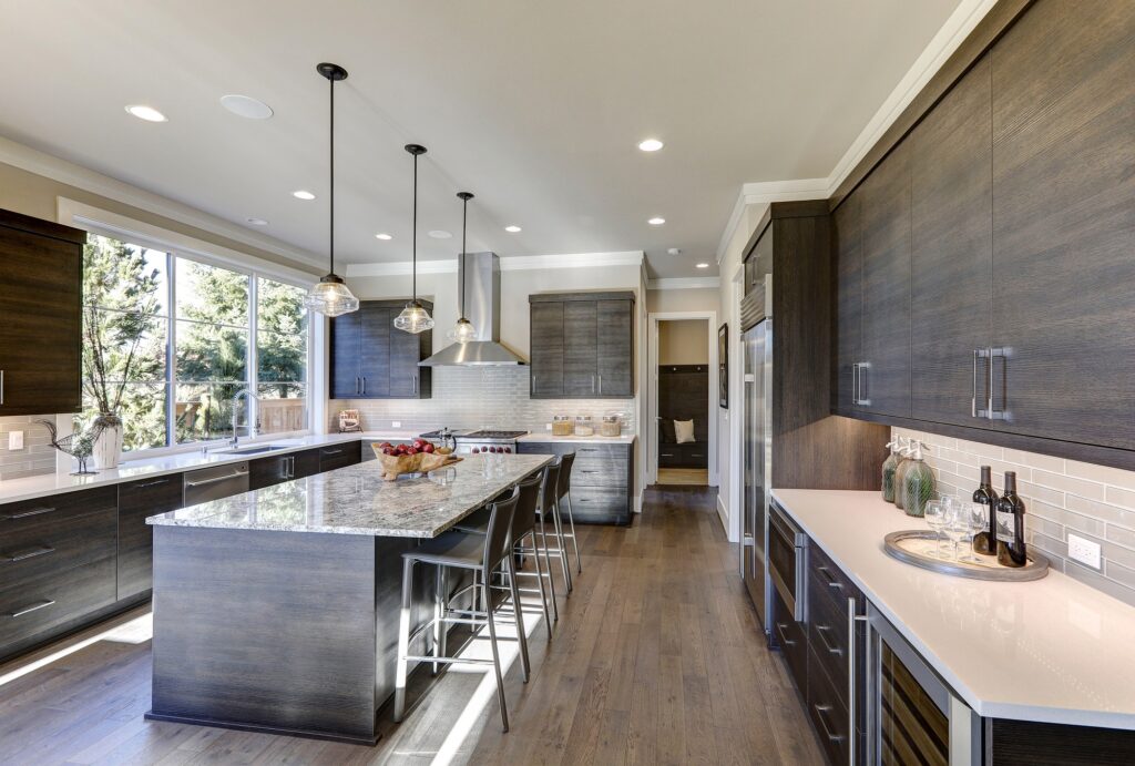 White quartz countertops and a glossy gray linear tile backsplash complemented by a bar style kitchen island with granite countertop